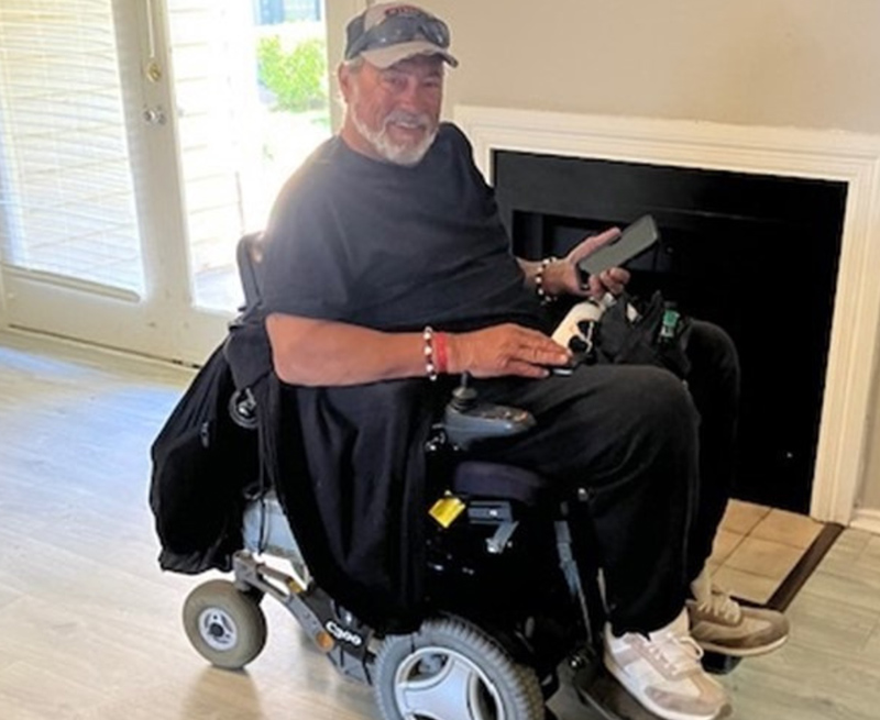 Happy man in wheelchair, holding cell phone in new apartment.